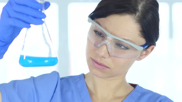 Scientist Looking at Blue Solution in Flask