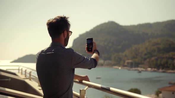 Man Taking Photo On Vacation In Resort. Man Takes Pictures On Smartphone On Seashore. Video Call.