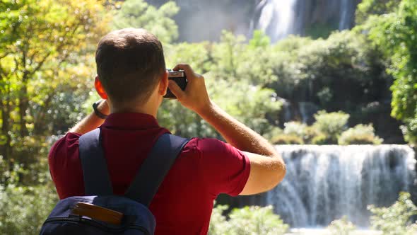 Young Man Blogger Zoomer Traveler Make Photo for Social Media of Amazing Waterfalls Nature on Trendy