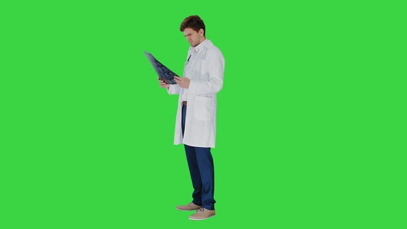 Concentrated Male Doctor Looking at Computed Tomography Xray Image on a Green Screen, Chroma Key.