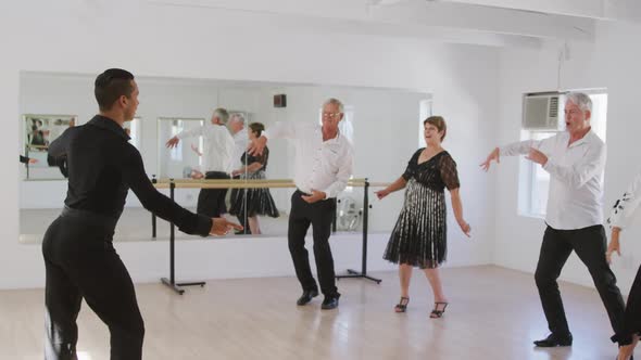 mixed race male dance teacher taking a ballroom dancing class at a dance studio