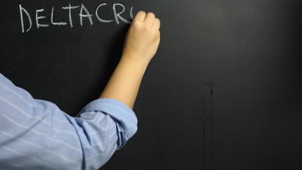 A woman's hand writes the word Deltacron in white chalk on a black board