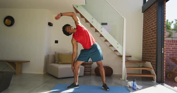 Fit african american man exercising at home and doing stretching at home