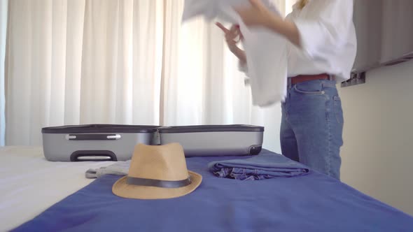 A young beautiful woman in a Santa Claus hat collects things in a suitcase