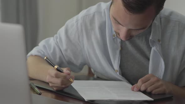 Man Sitting at the Table Correcting His Essay Wrote on the Paper at Home. Profession Concept, Writer