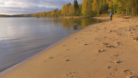 A Man Runs Along the Lake on a Sandy Beach. Early in the Morning at Dawn