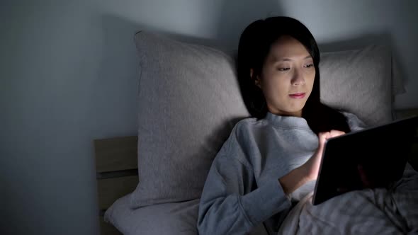 Woman browsing internet on bed at night