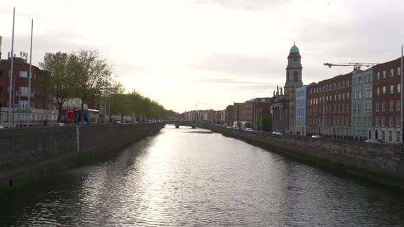 Liffey River With Traffic And Buildings On Both Sides At Late Evening In Dublin City, Ireland. - wid