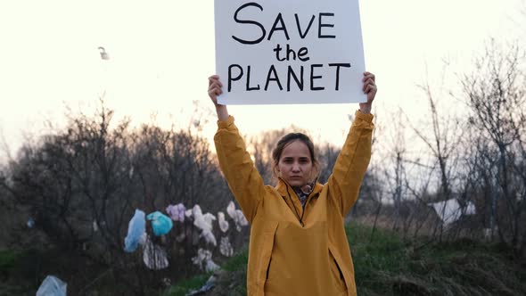 Portrait of a Young European Girl in a Huge Garbage Dump with Posters for Environmental Activists