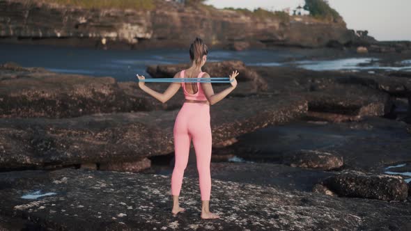 Back View Sexy Woman Doing Exercises Outdoor with Blue Elastic Band