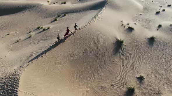 Aerial Footage of Three Young Women Walking on Top of a Sand Dune Rub Al Khali