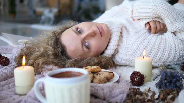 Beautiful Young Woman In Pullover Lies On Decorated Knitted Rug