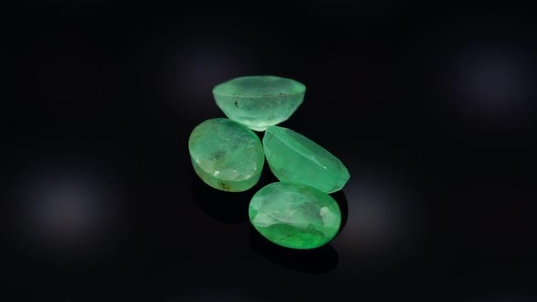 Natural Green Emerald on the Turning Table on the Black Background