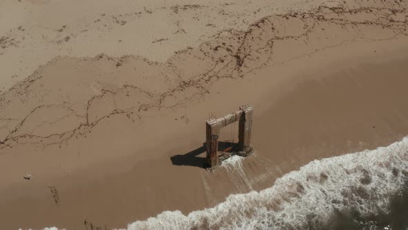 Aerial View of old broken pier made of cement in the middle of the ocean near Santa Cruz California.