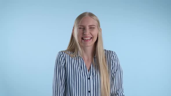 Happy Young Lady Bursting in Laughter on Blue Background