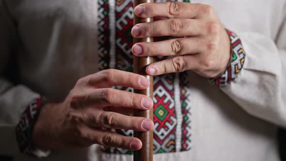 Hands of Man Playing on Woodwind Wooden Flute  Ukrainian Sopilka on Dark Background