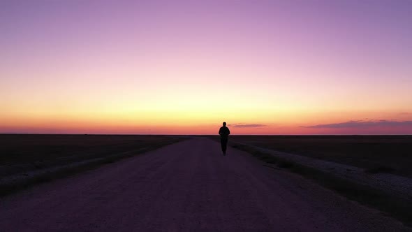 Sunset And Man Walking In Dirt Road Alone