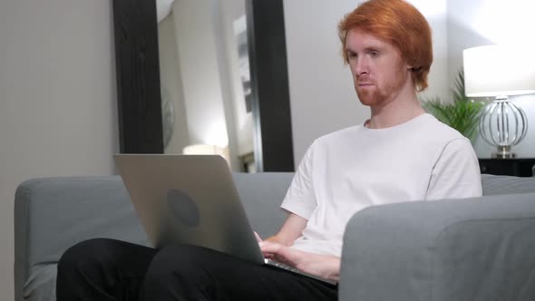 Casual Redhead Man Working with Laptop in His Lap