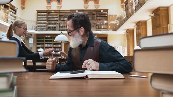 Angry Senior Grandfather Telling to Grandchildren to be Quiet in the Library while He Reading Book