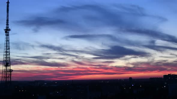 Time lapse of pink blue sky with moving purple clouds and silhouette of 5G communication tower