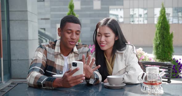 Two Beautiful Multiethnic People Close Friends Talking Together Looking at the Smartphone Gossiping