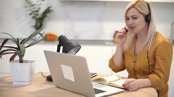 Woman in Headphones Communicates By Video Call on a Laptop