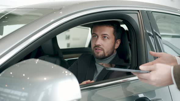 Car Buyer Talking To Dealer in Dealership Inside Shiny New Car Taking Key Fob