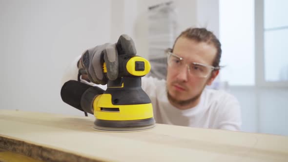 Carpenter in Protective Gloves and Glasses for Working on Wood Grinding Machine