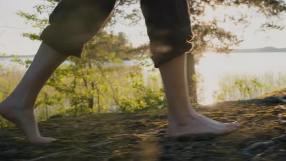 Legs of Man Walking on Forest Path Near River Closeup