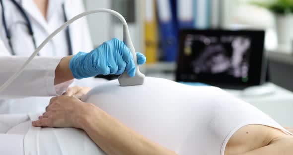 Ultrasound Scanner Device in Hands of Professional Doctor Examining Belly of Pregnant Woman