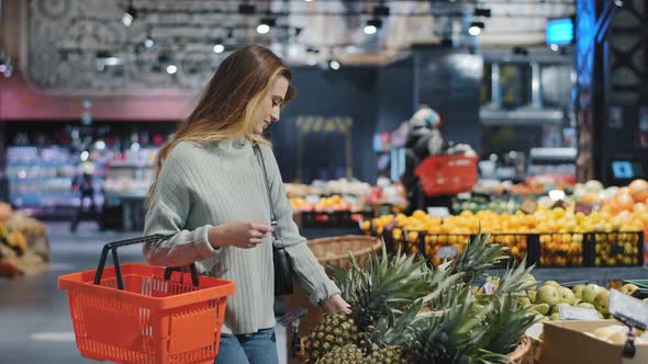 Young Female Shopper Chooses Ripe Juicy Healthy Fruits in Grocery Store Near Counter for Healthy