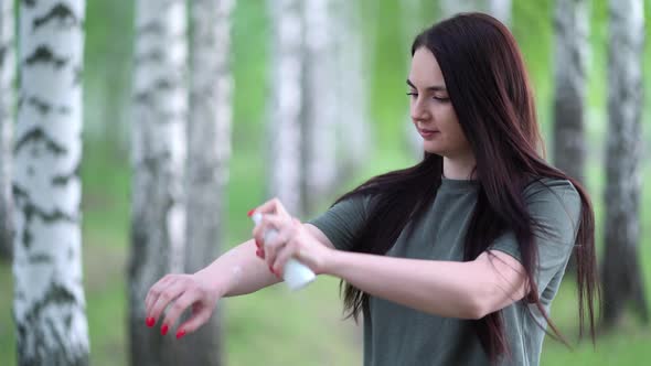 Young Woman in a Birch Grove Puts a Mosquito Repellent on Her Skin.