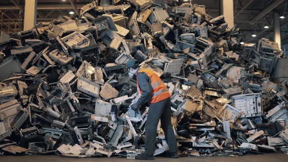 Debris of Office Machines are Getting Sorted By a Dumpsite Worker