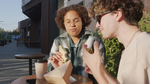 Girl and Guy Eating Sandwiches Outside