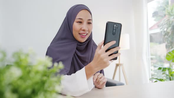 Asian muslim business woman using smartphone talk to friend by video chat brainstorm online meeting.