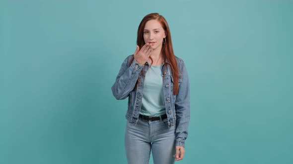 Beautiful Young Woman Looking at the Camera Blowing a Kiss with Hand on Air