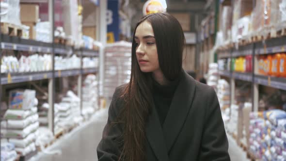 Woman choosing some stuff in hardware store. Pushing shopping cart buying materials in house improve