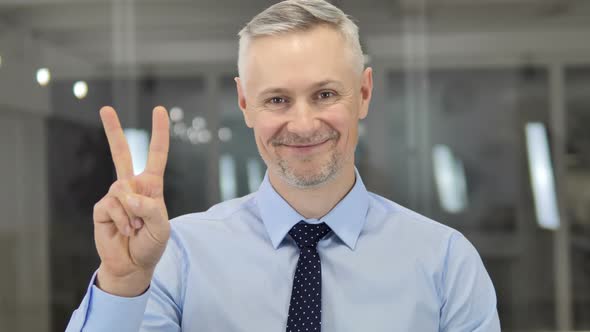 Victory Sign By Positive Grey Hair Businessman