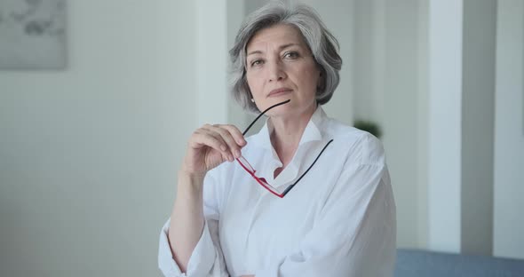 A Beautiful Confident Older Woman Architect is Taking Off Her Glasses and Looking at the Camera