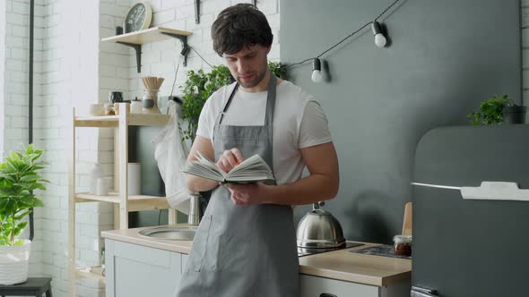 Man Cooking in Kitchen Reading Recipe From Cookery Book