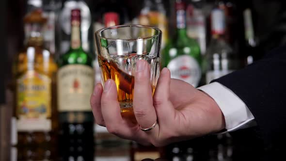 Close Up of Man's Hand Holding Crystal Glass of Whiskey or Brandy