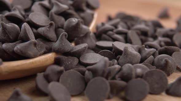 Chocolate sprinkles fall into a heap in a wooden spoon in slow motion. Macro