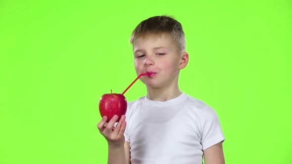 Little Boy Is Holding an Apple with a Straw, Showing Thumbs Up. Green Screen. Slow Motion