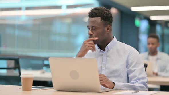 African Businessman with Laptop Thinking at Work