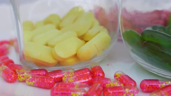 Rotating shot of colorful tablets in glass bottle and capsule around