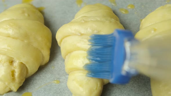 Close Up Applying of an Egg Yolk with Silicone Brush on Italian Croissants