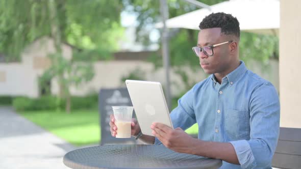 Attractive African Man Using Tablet in Outdoor Cafe