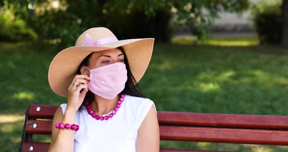 Woman in Straw Hat Takes Off Pink Protective Mask