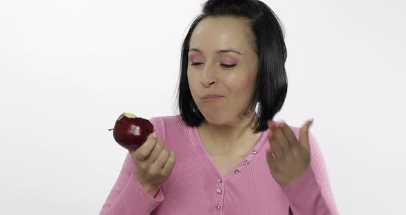 Young Beautiful Woman Eating Big, Fresh and Juicy Red Apple on White Background