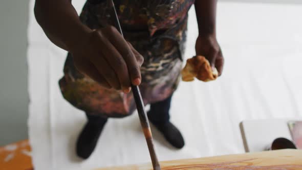 Overhead view of mid section of african american male artist painting on canvas at art studio